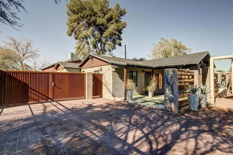 Front of the house with a red fence and desert landscaping